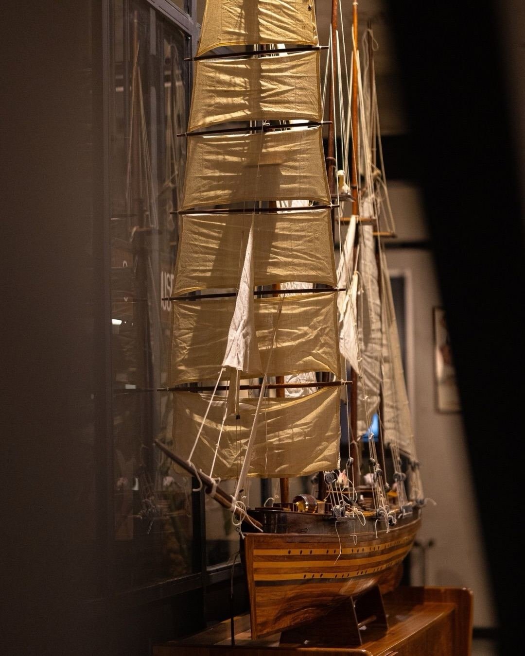A large model schooner with linen sails, lit warmly