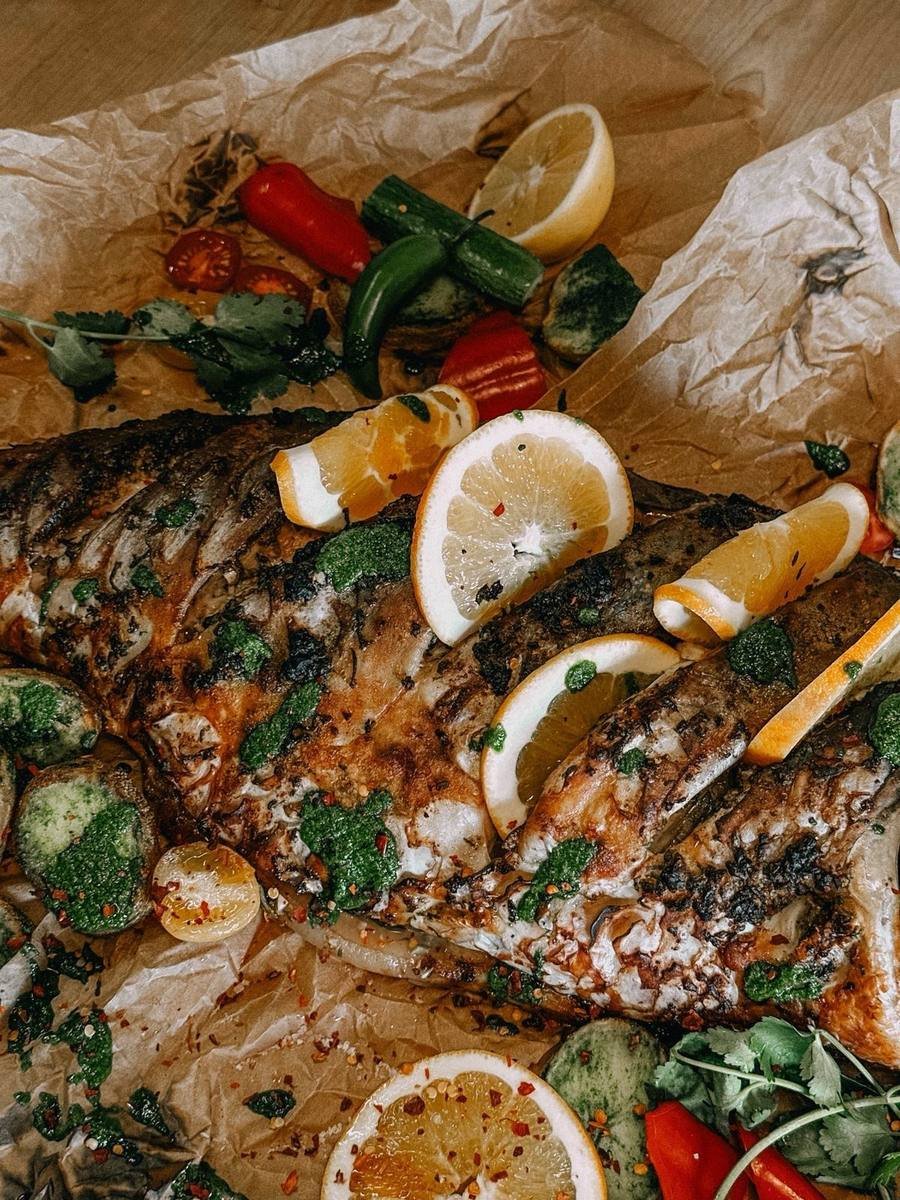 Close-up of charred fish with lemon and green adjika
